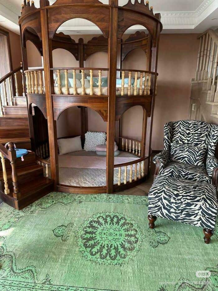 An example of grand-scale questionable home decor featuring a massive, two-story ornate wooden bunk bed designed like a royal gazebo, squeezed into a room alongside a clashing zebra-print armchair.