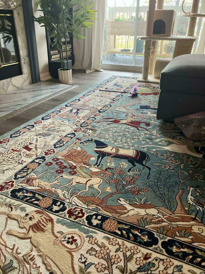 A close-up of an intricate, maximalist area rug featuring a dense, ancient-style pattern of horses and trees, contributing to a busy and visually demanding questionable home decor aesthetic.