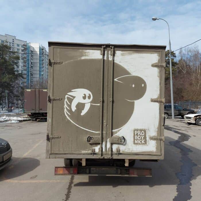 Minimalist character art etched into a circle of dirt on back of a truck.