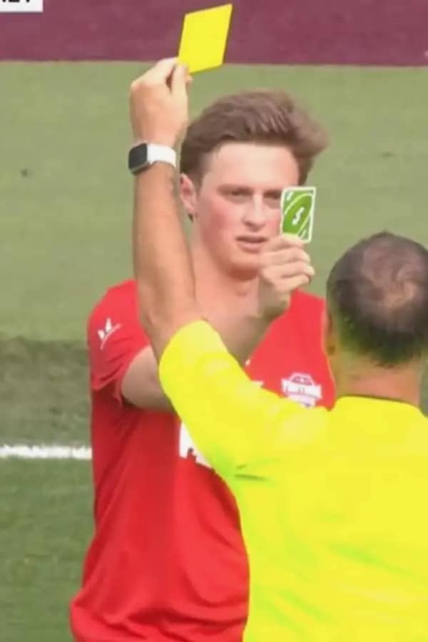 A legendary sports-themed dumb meme showing a soccer player during a match pulling an absolute power move. As the referee raises a yellow card to penalize him, the player holds up a green Uno "Reverse" card directly to the official’s face with total sincerity.