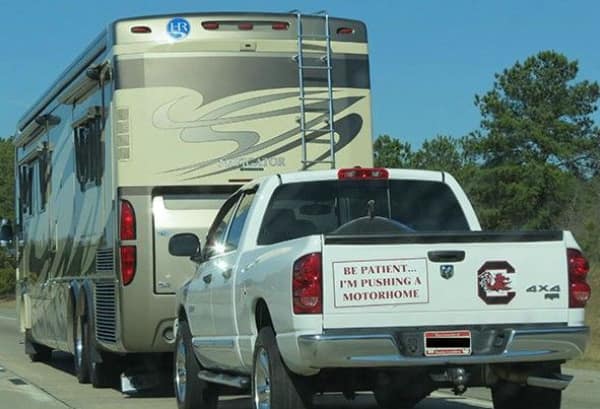 A funny bumper sticker on a chrome metal bumper that reads Sorry For Driving So Close In Front Of You in black text on white, sarcastically addressing tailgaters.