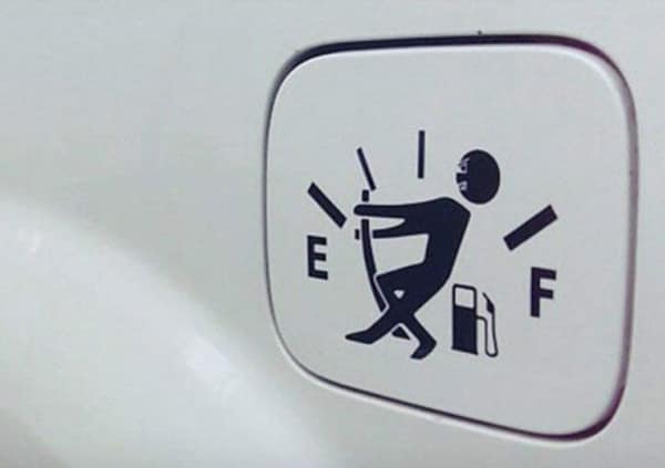 A black hatchback showing a [funny bumper sticker] applied directly to the rear glass near the wiper. The sticker features simple white line text and a drawing of a stick figure walking, stating: "I AM NOT SLOW. I AM SIMPLY SAVING FUEL BY DRIVING THE SPEED LIMIT."
