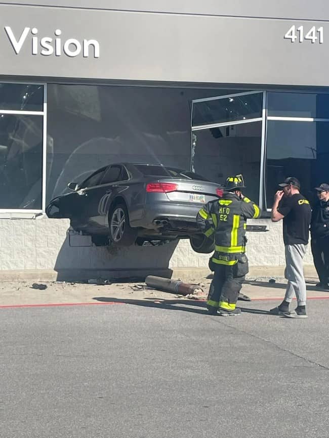 Gray Audi sedan crashed through front wall of Vision business storefront with firefighters assessing damage