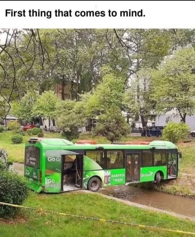 Green Go Green city bus from Tirana Albania fully submerged in shallow pond with doors open captioned first thing that comes to mind