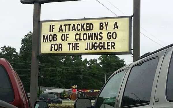 A roadside marquee sign joking that if attacked by a mob of clowns go for the juggler.