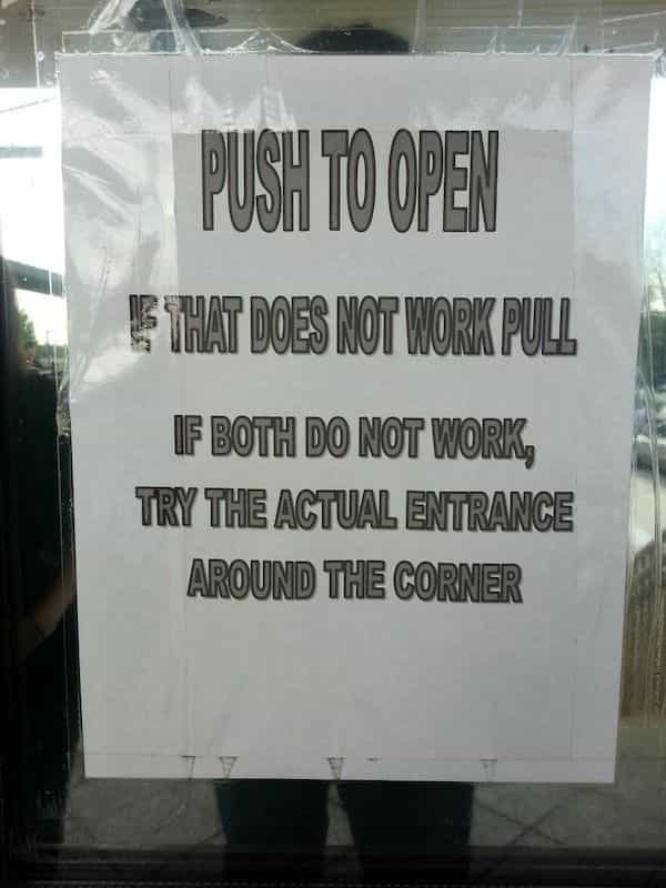 A confusing door sign with instructions to push, pull, or try the actual entrance around corner.