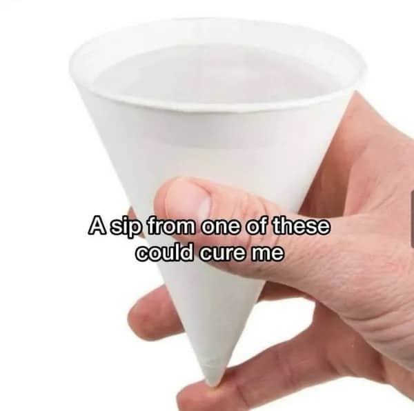 A white paper cone water cup held by a hand with funny meme text about curing problems.
