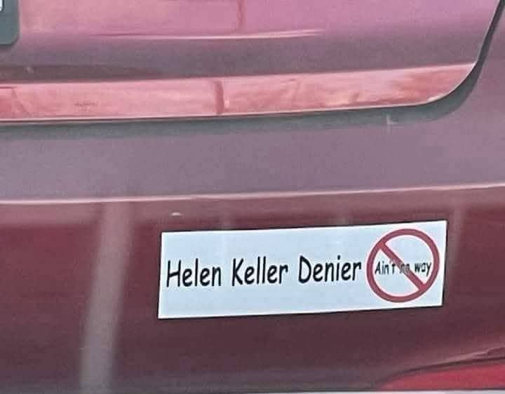 Bumper sticker on a car that reads Helen Keller Denier with a funny circular cross-out symbol.