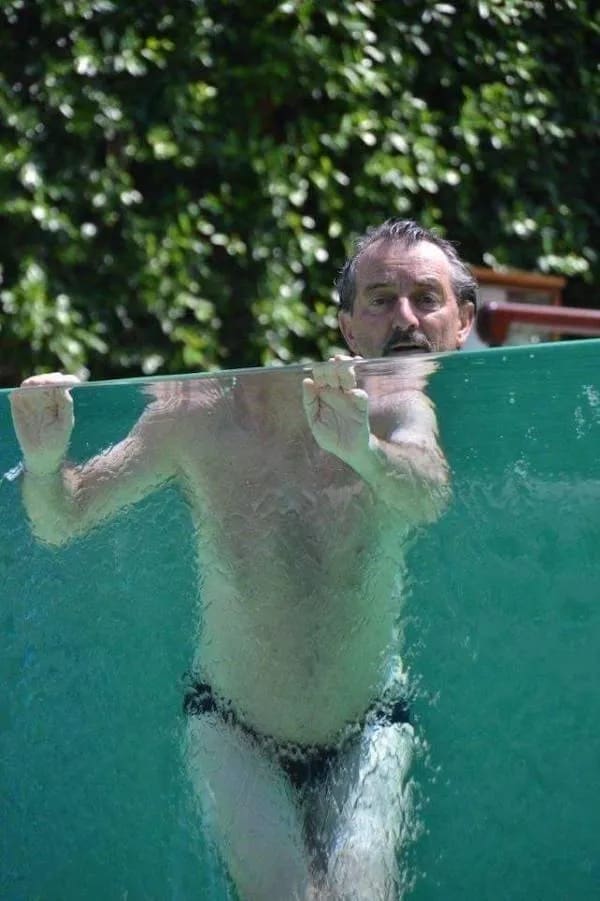 Perspective photograph of a man in a pool with a distorted, tiny-looking body underwater.