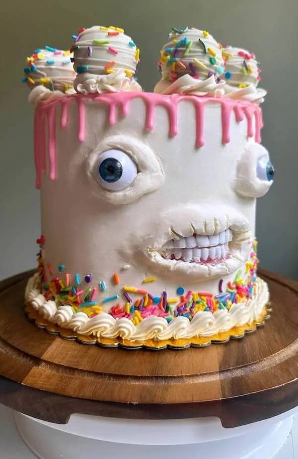 Cursed image of a white cake decorated with realistic human eyes and a mouth with teeth.