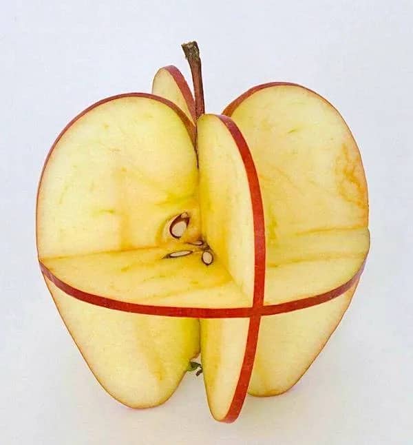 An apple creatively sliced and reassembled into a geometric, cross-sectioned spherical shape against a white background.