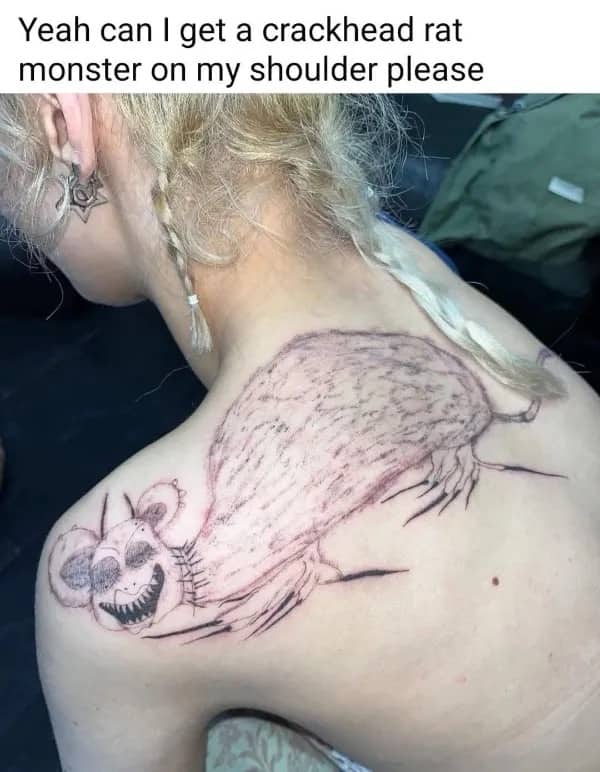 Poorly executed shoulder tattoo of a creepy rat monster with sharp teeth and messy lines.