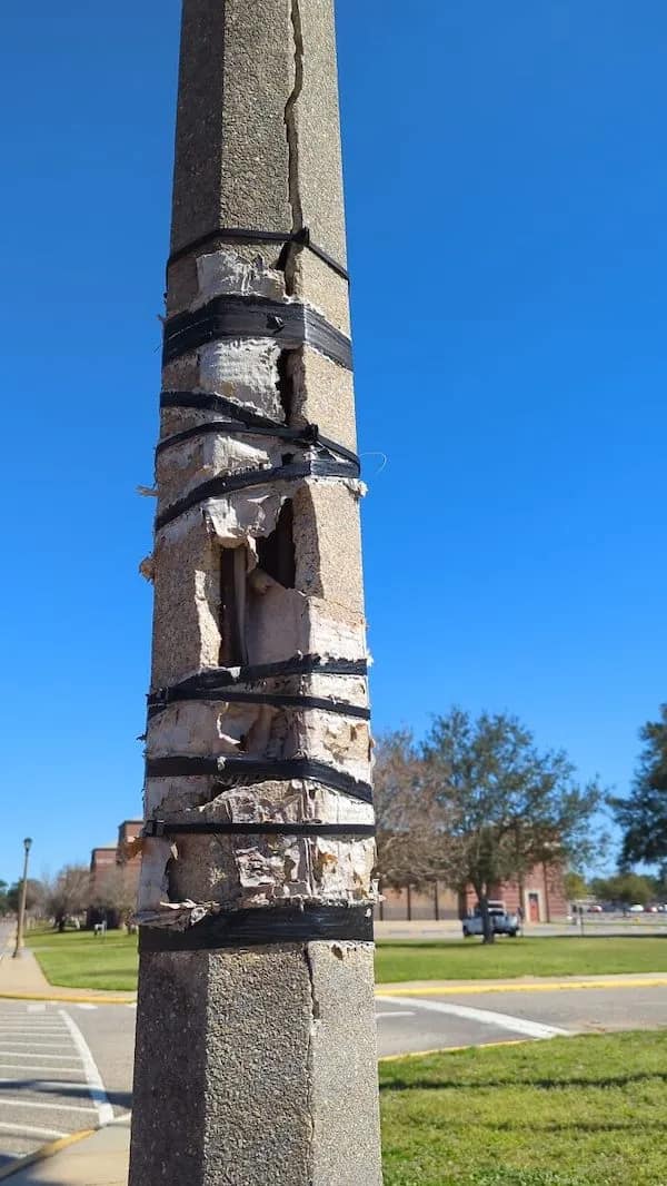 A funny Osha violation picture of a structural concrete pillar with a massive vertical crack being "repaired" with nothing but a series of black industrial zip ties.