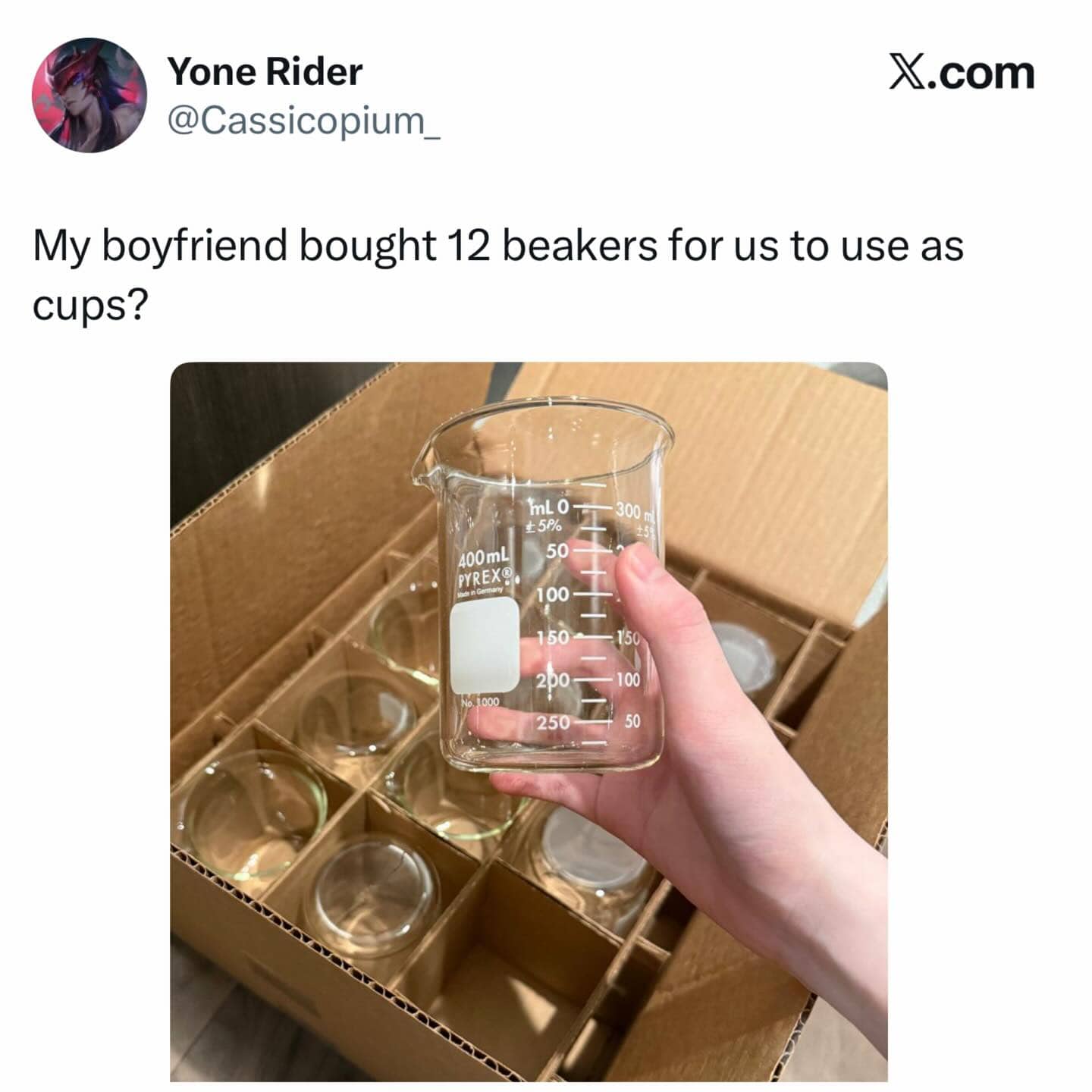 Hand holding a Pyrex laboratory beaker from a box of twelve used as drinking cups.