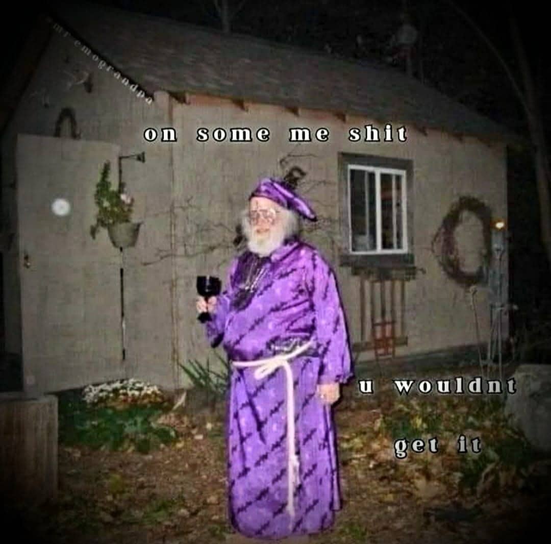 Man in a purple wizard costume holding a glass of wine in front of a shed.