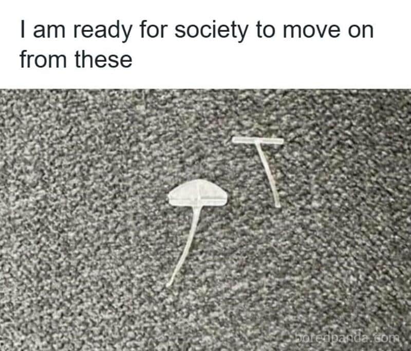 A minimalist funny relatable meme showing two clear plastic "T-bar" clothing fasteners lying on a grey carpet. The text expresses a collective societal exhaustion with these tiny, annoying fasteners that are impossible to remove without scissors.