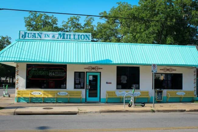 Juan in a Million Tex-Mex restaurant exterior with turquoise roof and yellow benches, classic name pun.