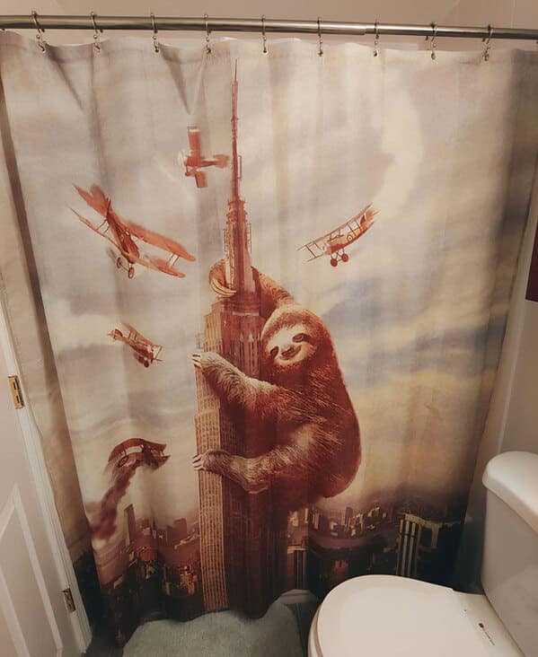 A cinematic funny shower curtain parodying King Kong. A giant, determined sloth is shown scaling the Empire State Building while biplanes swarm around it, capturing the most low-speed, high-stakes monster movie ever imagined.