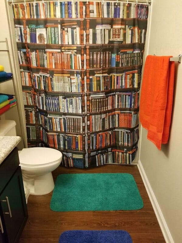A literary-themed funny shower curtain designed to look like a massive, floor-to-ceiling wooden bookshelf packed with rows of colorful, vintage hardcover books, turning a standard bathroom into a secret library.
