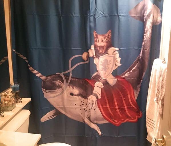 A surreal and epic funny shower curtain featuring a cat in full silver plate armor, holding a regal shield, and heroically riding a narwhal through deep blue ocean waters.