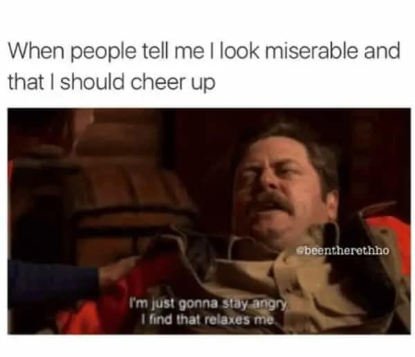 A classic screen capture of Ron Swanson from Parks and Recreation looking profoundly unamused. The grumpy meme text shuts down anyone suggesting he "cheer up," with a subtitle explaining that staying angry is actually relaxing for him.