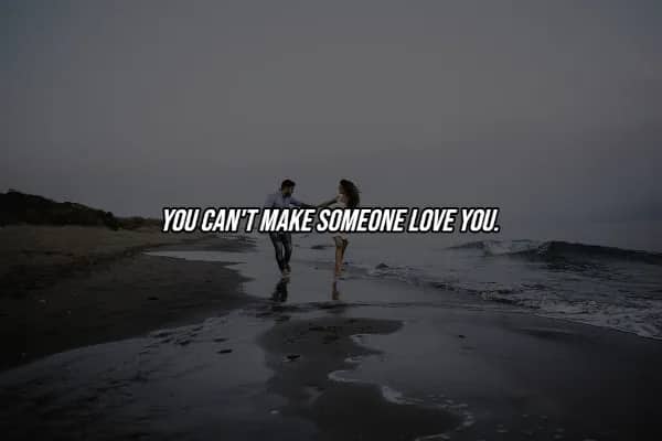 Two people running on moody beach with hard truth quote stating you cannot make someone love you