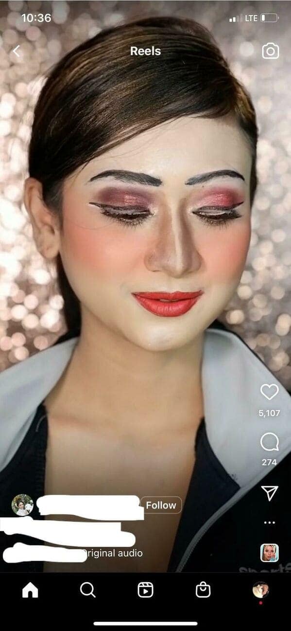 A low-quality makeup fail from a social media reel. The subject features unblended white lines directly under the eyebrows and a stark white nose highlight that fails to blend into the patchy red and black eyeshadow.