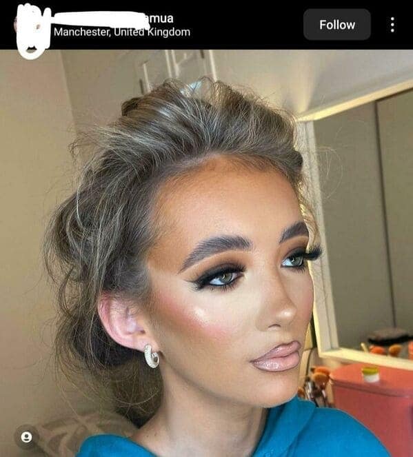 A dramatic makeup fail where heavy orange foundation stops abruptly at the hairline, leaving a startling white gap at the scalp. The look is completed with massive, oversized "fan" lashes and pale, overlined lips.