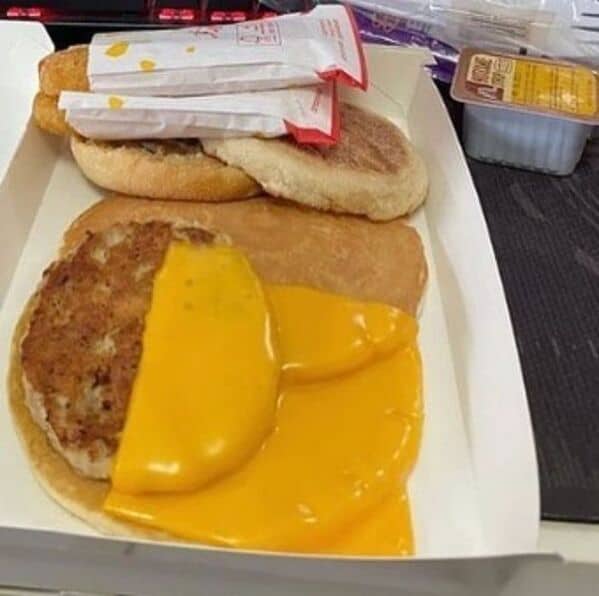 McDonald's breakfast McMuffin fail with sausage patty and cheese oozing out messily onto tray