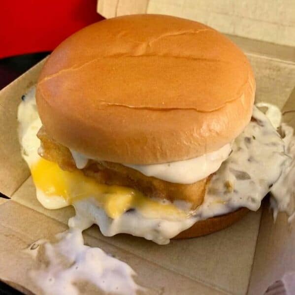 McDonald's fish sandwich drowning in excessive tartar sauce with cheese oozing out of bun
