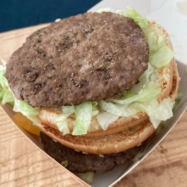 McDonald's burger fail showing massive patty extending far beyond small bun with lettuce underneath