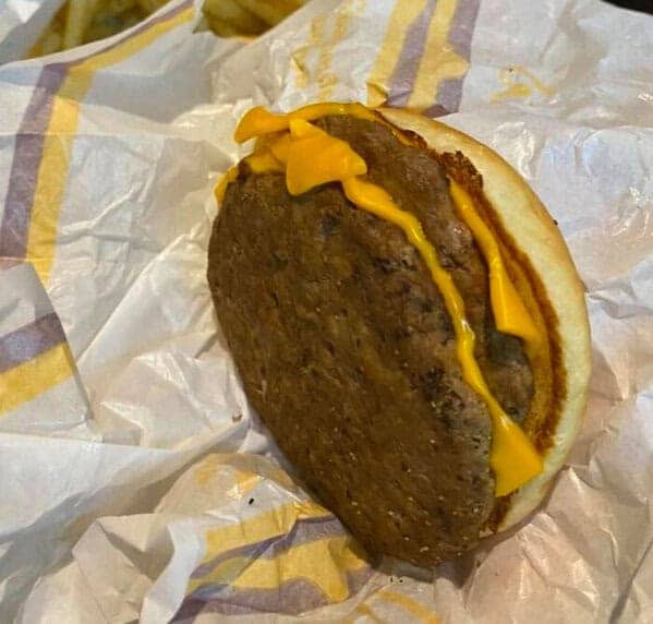 McDonald's burger fail with oversized patty extending beyond the bun with single stripe of cheese