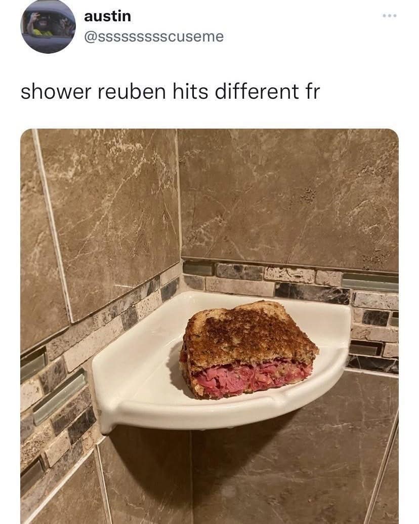 A chaotic meme dump photo from the bathroom of user austin. A thick, toasted Reuben sandwich is shown resting precariously on a white ceramic shower shelf where the soap usually goes, with the definitive caption: "shower reuben hits different fr."
