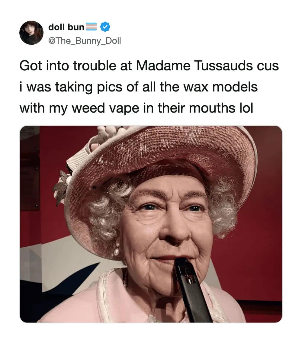A controversial and viral meme dump post from @The_Bunny_Doll. It features a wax figure of Queen Elizabeth II at Madame Tussauds, looking directly at the camera with a black vape pen placed in her mouth. The caption admits the user got into trouble for doing this to all the models.