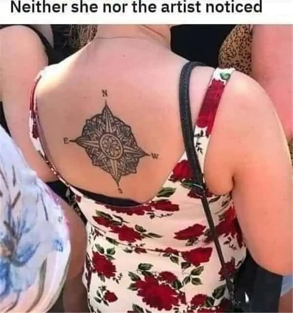 A cringeworthy "tattoo fail" funny meme. A photo shows a woman’s back with an intricate compass tattoo, but the East (E) and West (W) markers are swapped. The caption notes that "neither she nor the artist noticed" the geographical blunder.