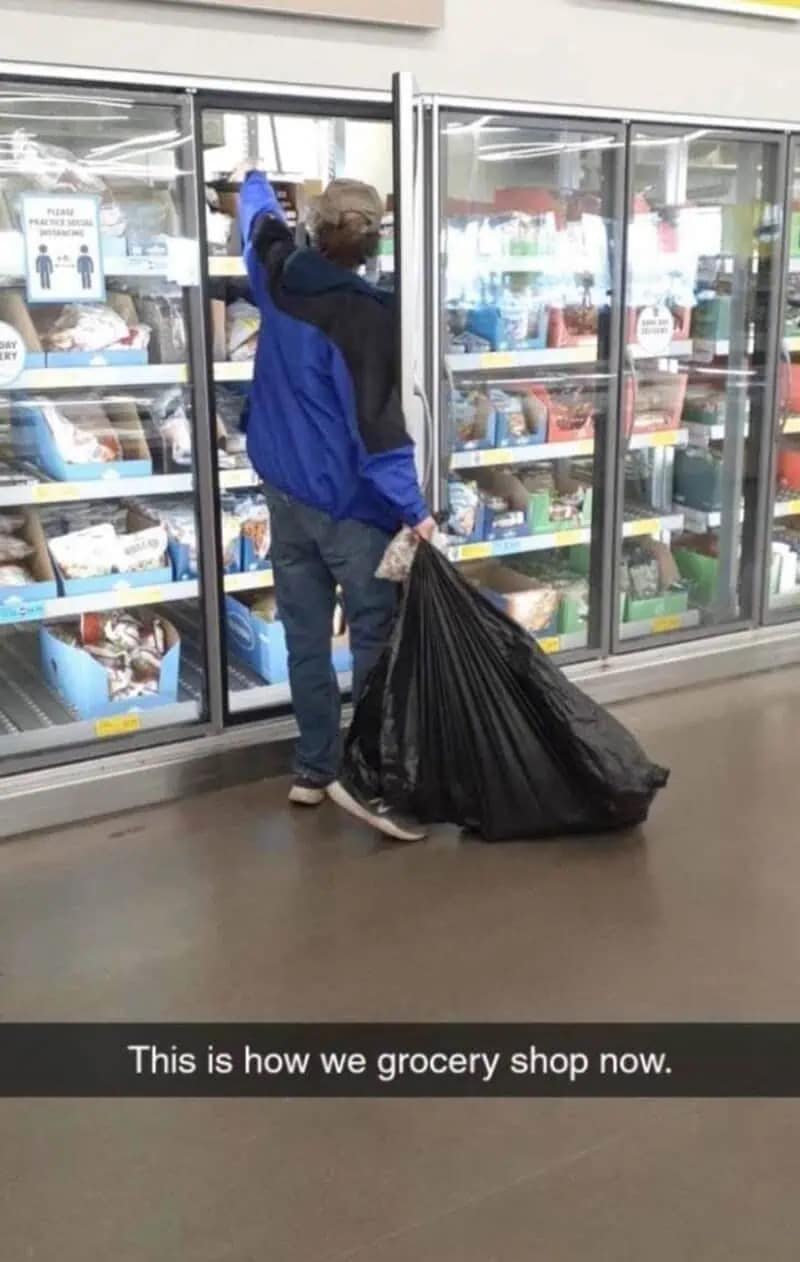 A chaotic meme dump photo of a man in a grocery store aisle dragging a massive, bulging black trash bag instead of using a cart. The Snapchat-style text reads, "This is how we grocery shop now."