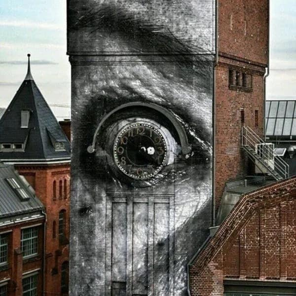 A surreal visual from a hilarious meme dump featuring a clock tower modified with street art. A hyper-realistic eye has been painted around the clock, turning the clock face into a pupil that appears to be staring intensely at the surrounding city buildings.