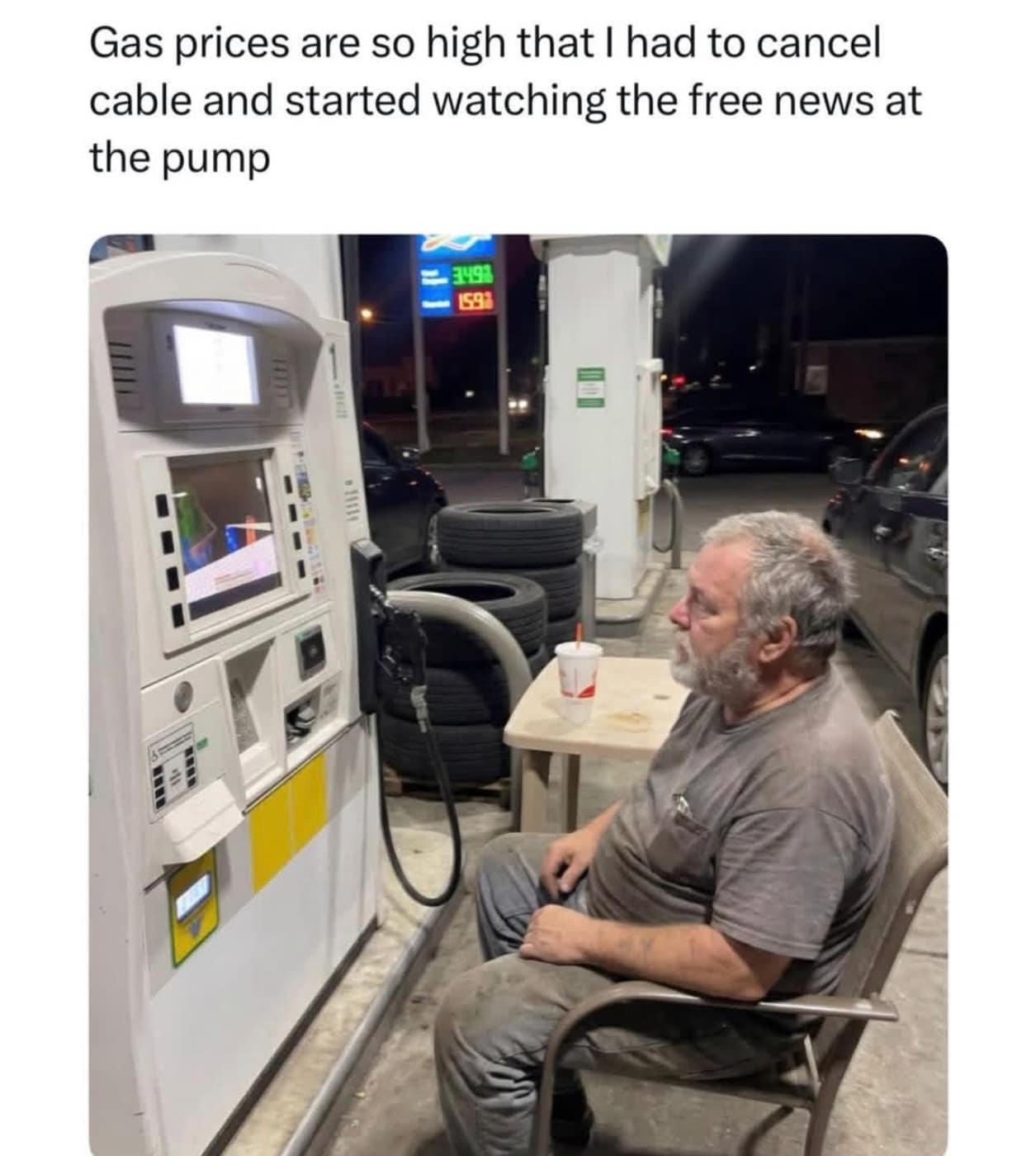 A bleakly funny commentary on inflation. An older man is pictured sitting in a lawn chair at a small table next to a gas pump, staring intently at the small news screen on the pump. The caption jokes that gas prices are so high he had to cancel cable and watch the "free news" at the station.