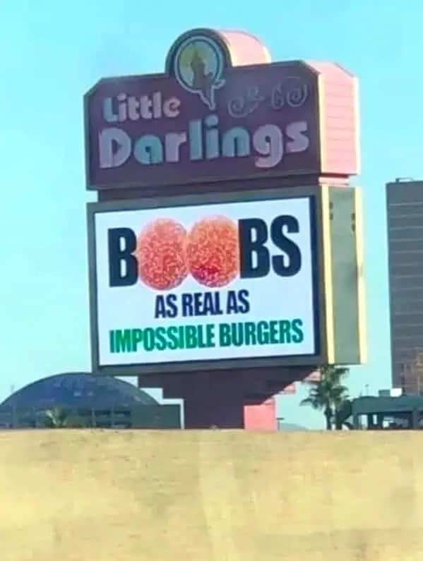 funny meme featuring a roadside billboard for "Little Darlings." The digital sign advertises "B**BS AS REAL AS IMPOSSIBLE BURGERS," using a clever fast-food comparison to imply they are plant-based or synthetic.