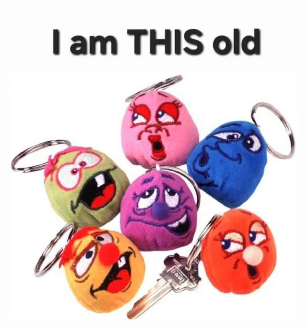 A final "I am THIS old" millennial meme featuring a pile of colorful, plush keychain characters with exaggerated, goofy faces and googly eyes, a ubiquitous accessory for every late-90s backpack.