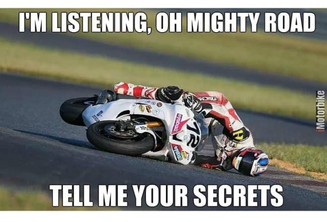 A hilarious motorcycle meme featuring a sportbike racer leaned so far over in a turn that their helmet is literally resting against the asphalt. The dramatic impact is lightened by the text: "I'M LISTENING, OH MIGHTY ROAD / TELL ME YOUR SECRETS."