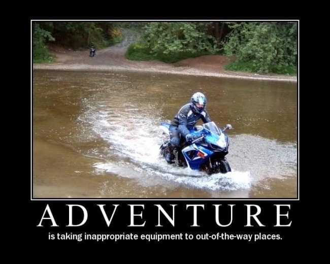 A classic motivational-style motorcycle meme showing a blue and white sportbike splashing through a shallow, wide river. The bold text below declares: "ADVENTURE is taking inappropriate equipment to out-of-the-way places."