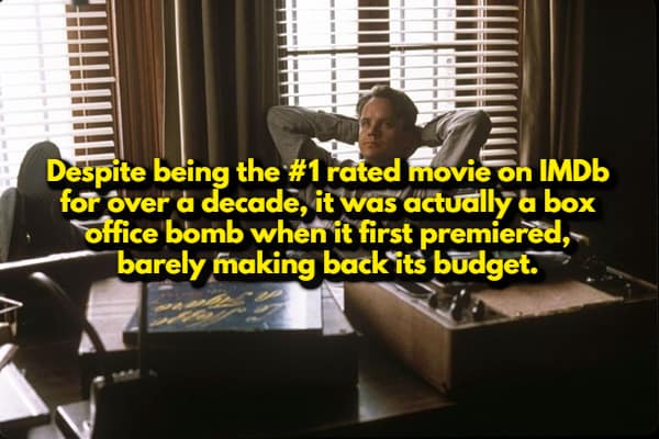 A random movie fact showing Tim Robbins as Andy Dufresne leaning back in his office. The text highlights a surprising irony: despite being the #1 rated movie on IMDb for over a decade, The Shawshank Redemption was actually a massive box office bomb upon its release.