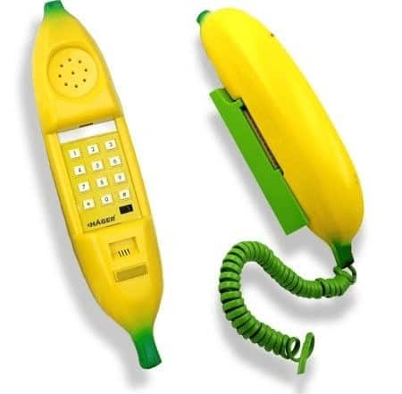whimsical novelty landline phone shaped exactly like a bright yellow banana. The handset is the fruit itself, featuring green-tipped ends and a keypad hidden along the inner curve