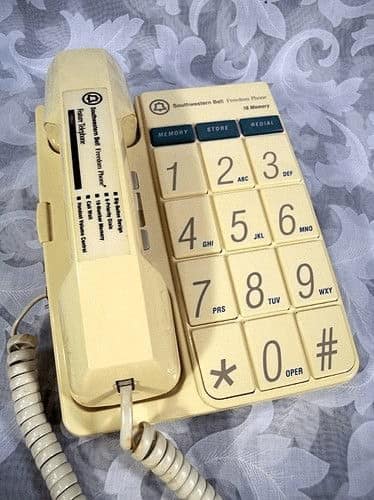 A vintage landline phone with oversized "Big Button" keys, designed for accessibility. The entire unit is a retro off-white cream color with teal-colored memory buttons at the top.