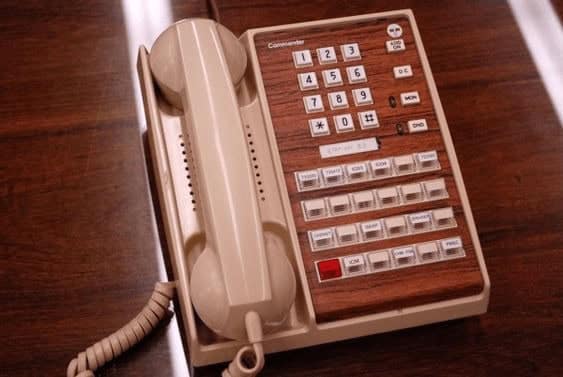 professional vintage landline phone with a "Commander" label, featuring a classic wood-grain faceplate. It has multiple rows of white buttons for office-specific functions
