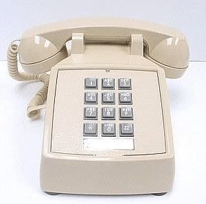 The quintessential vintage landline phone, a standard beige desk model with a square push-button keypad and a thick coiled cord, representing 20th-century office utility.