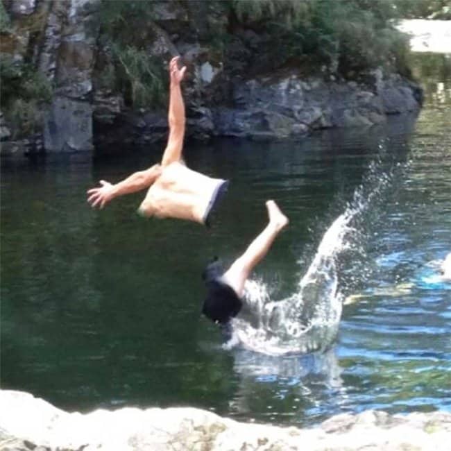 A man jumping into a lake appearing as a floating torso and separate legs.