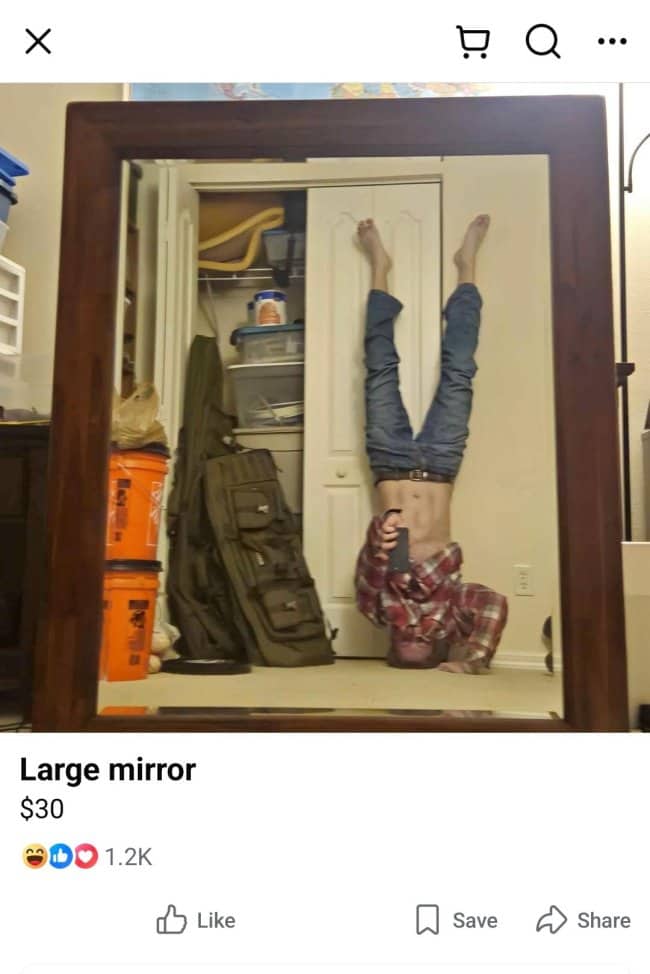 Wooden framed mirror for sale reflecting man doing headstand in messy closet area