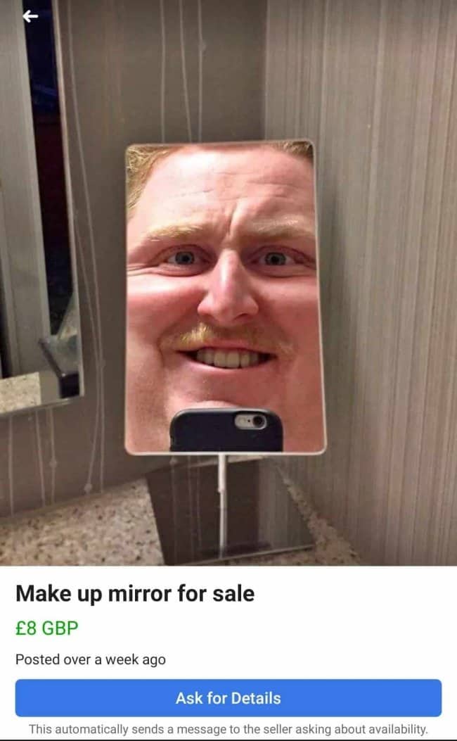 Makeup mirror for sale reflecting close up distorted smiling man's face with mustache
